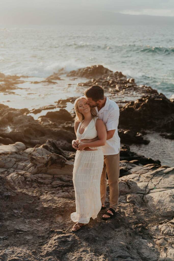maui beach at sunset with couple standing and waves crashing against lava rocks